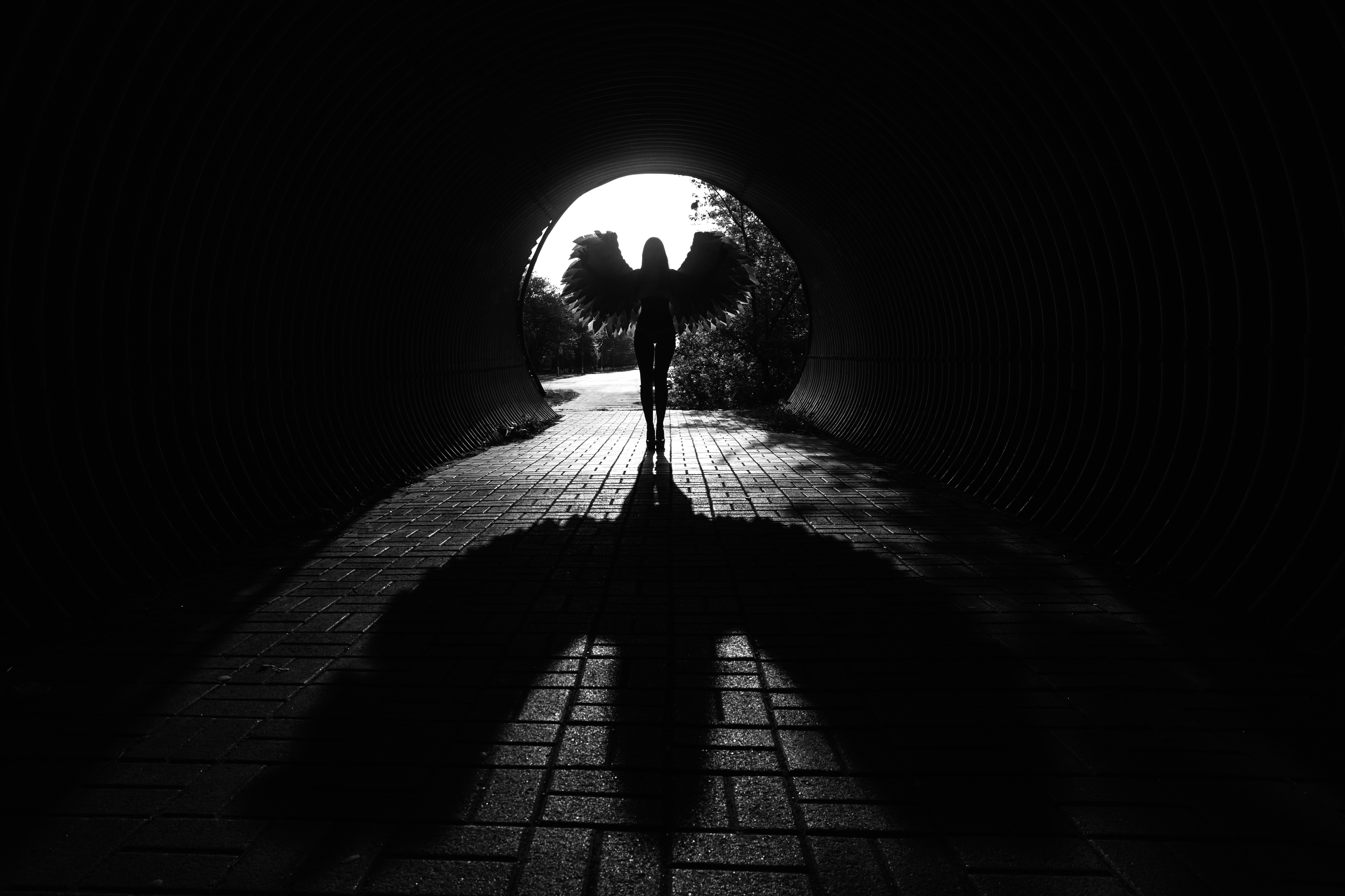 figure with wings at the mouth of a dark tunnel
